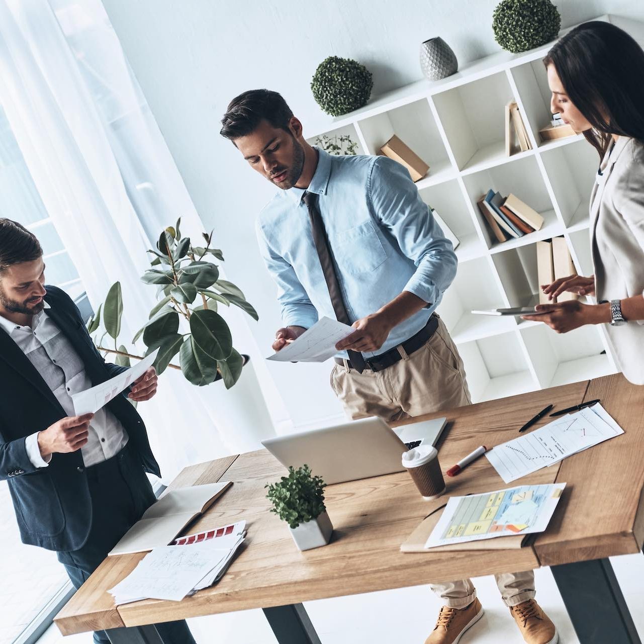 Successful business team. Top view of young modern people in smart casual wear discussing business while standing in the creative office